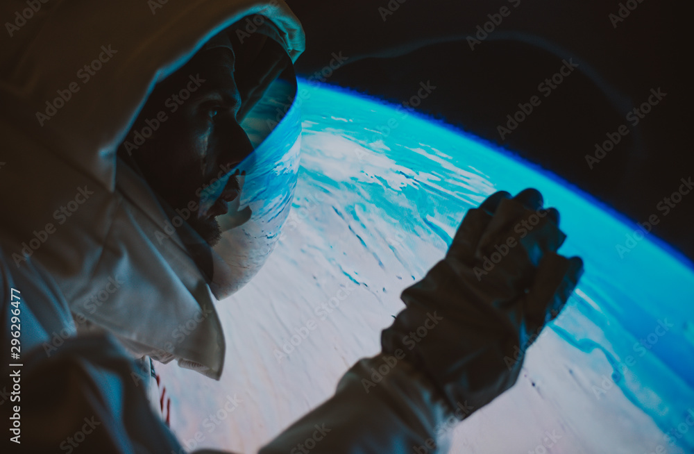 Poster astronaut looking planet earth from the window of his capsule. concept about science and space explo