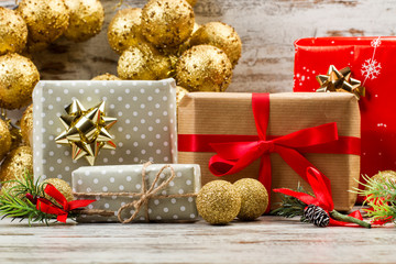 Fototapeta na wymiar Regalo de Navidad con bolas dorada vista de frente sobre mesa de madera rústica