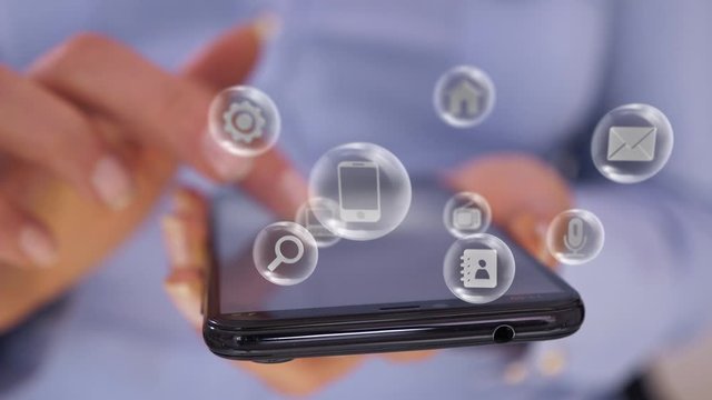 Woman hand touch smartphone screen, various application icons pop up, revolve floating around as a futuristic virtual interface. Connect to the future and the world through cloud services concept.