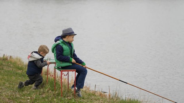 Little kid watching small fish caught by big brother