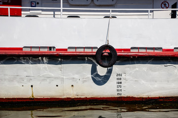 A tire from a car tied by a rope weighs on a white boat..