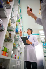 man doctor and woman pharmacist in charge of checking inventory list of medicine remaining or...