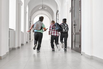 Group of schoolboys with school backpacks running.