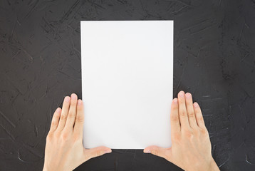 Naklejka premium Man holding brochure with blank cover on worn black background. Mock up for design.