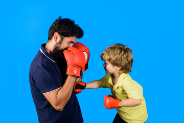 Little kickbox fighter hitting with his coach. Dad and his son in boxing gloves. Child and...