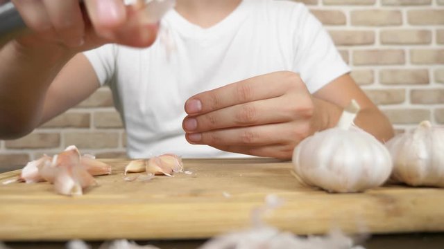 closeup head of garlic, male hands peel the garlic on a wooden board