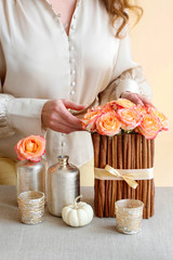 Floral arrangement with roses and cinnamon sticks stands on the table