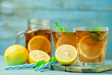 Iced tea with lemon slices and mint on wood background
