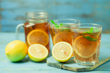Iced tea with lemon slices and mint on wood background