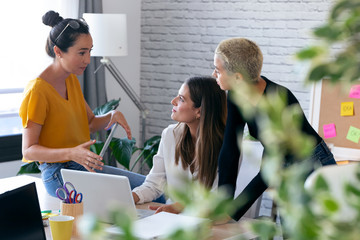 Three modern female entrepreneurs who talk about new ideas for to next work in a joint workspace.