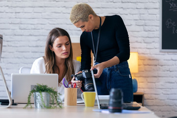 Modern entrepreneur women reviewing last photographs in the camera for they next work in the office.