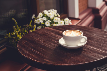 View of a summer terrace cafe with cup of cappuccino on the table.