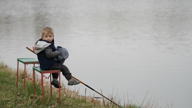 Little kid fishing alone on river bank