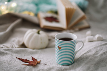 Autumn still life. A cup, dried leaves, book and pumpkin. Hygge lifestyle, cozy autumn mood. Flat lay, thanksgiving background
