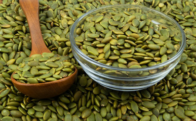Green pumpkin seeds and wooden spoon with glass bowl