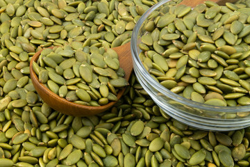 Green pumpkin seeds and wooden spoon with glass bowl