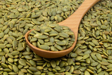 Green pumpkin seeds and wooden spoon