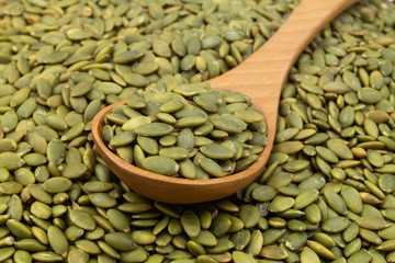 Green pumpkin seeds and wooden spoon