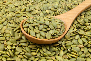 Pumpkin seeds and wooden spoon close up