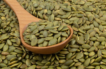 Pumpkin seeds and wooden spoon close up