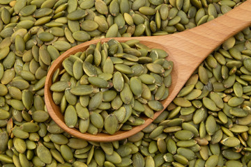 Pumpkin seeds and wooden spoon close up