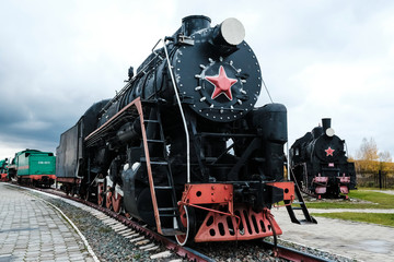 Fototapeta na wymiar Old Russian locomotive. Steam locomotive with red wheels. Retro locomotive on rails. Black locomotive..