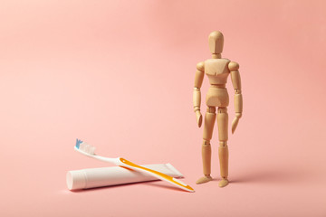 Oral hygiene and dental care. Wooden man holds toothbrush and toothpaste.