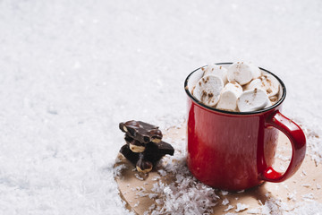 Obraz na płótnie Canvas Mug with marshmallows near chocolate on stand between snow