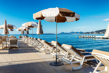 A row of deck chairs with orange mattresses on a sandy beach. Bright sunny day at the resort. Beautiful landscape.