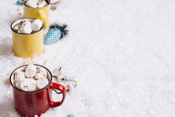 Cups with sweet candies near Christmas toys between snow