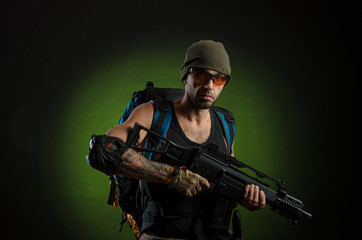 a man with a gun and a backpack on a dark background with emotions looking, aiming, watching, sneaking