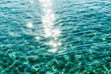 Transparent turquoise surface of sea water with sun glare. Background, space for text.