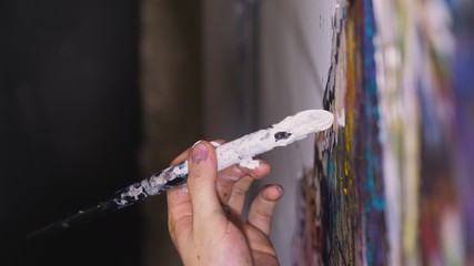 Artist designer draws an eagle on the wall. Craftsman decorator paints a picture with acrylic oil color brush. Close-up dark magic cinematic look.