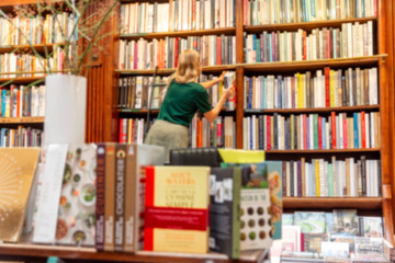 Girl chooses a book in a large bookstore, standing on the stairs. Blur.