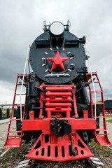 Old Russian locomotive. Steam locomotive with red wheels. Retro locomotive on rails. Black locomotive with red star.