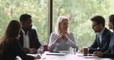 Smiling mature female leader discuss project with team at meeting