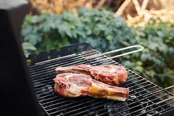 selective focus of raw meat grilling on barbecue grid outside