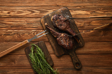 top view of meat and greenery on cutting boards with grill tools