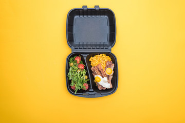 top view of eco package with corn, meat, fried eggs and salad isolated on yellow