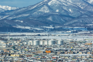 view of city; chemical tank plant and snow mountains in the winter
