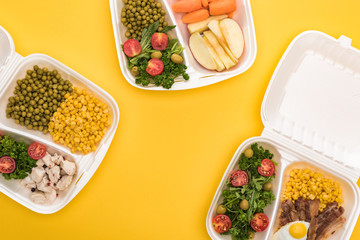 top view of eco packages with apples, vegetables, meat, fried egg and salads isolated on yellow