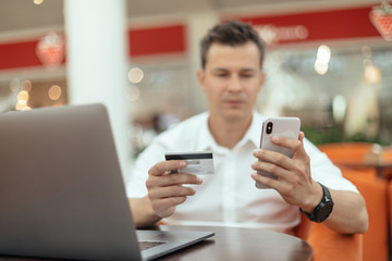 Man using smartphone and laptop computer for online shopping . Credit card