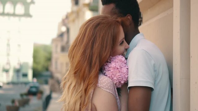 Young couple in love standing and tenderly cuddling on streets of European cities