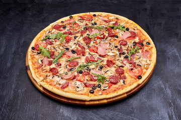 Fresh pizza Campania on wooden cutting board. isolated on dark background.