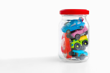Toy cars in glass bottle. Unusable cars, automobiles. Traffic Jam in transparent jar on white background. Traffic jams on the road. Conceptual