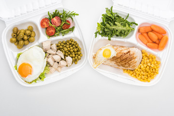 top view of eco packages with arugula, vegetables, meat, fried eggs and salad on white background