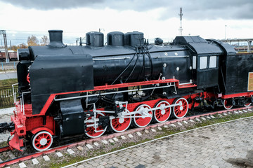 Old Russian locomotive. Steam locomotive with red wheels. Retro locomotive on rails. Black locomotive with red star.