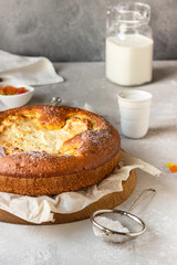 Open pie with cottage cheese filling on a wooden cutting board with milk. Healthy children breakfast or snack.