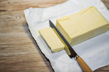 A piece of frozen butter on paper, on the background of an old wooden table vintage, rustic style,...