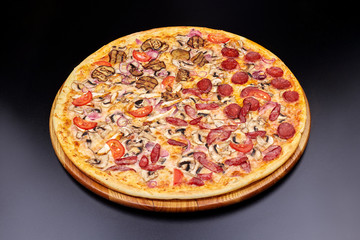 Pizza "Four Seasons" on wooden board on black concrete